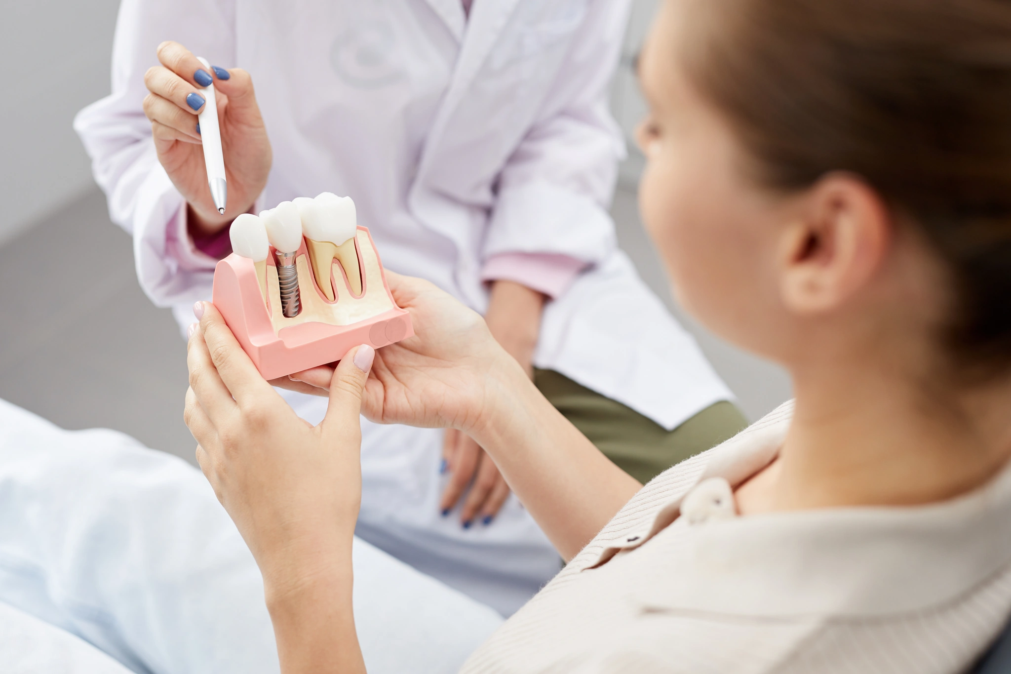 Pacjentka trzymająca model implantu zębowego podczas konsultacji stomatologicznej